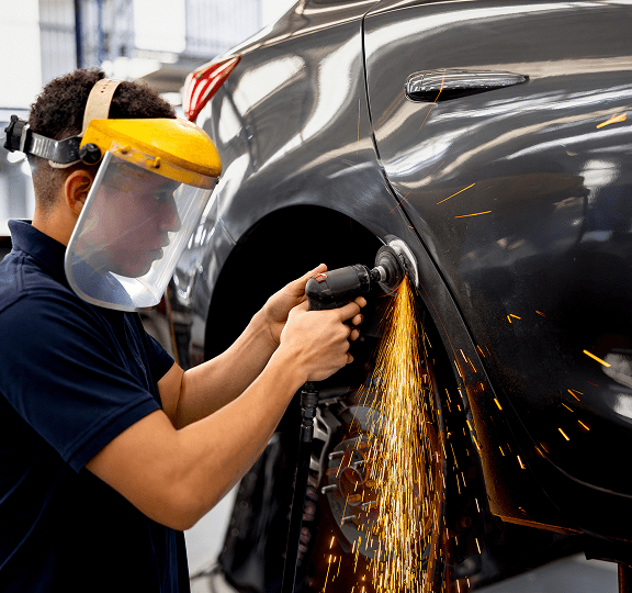 Worker sanding car with sparks flying