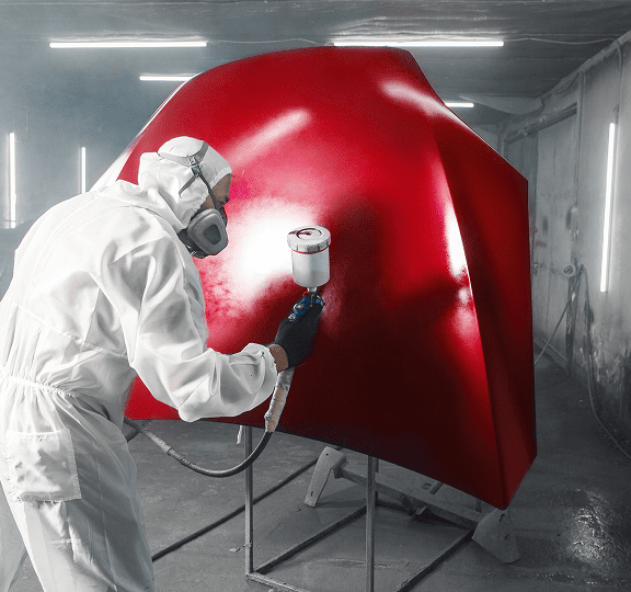 Technician painting car hood in workshop